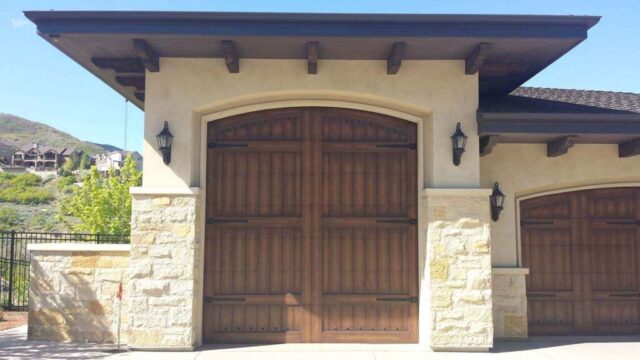 Custom carriage house door set in stucco and stone garage facade in San Jose, CA