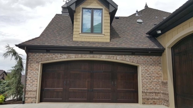 Elegant carriage house door set in brick exterior under dormer window in San Jose, CA